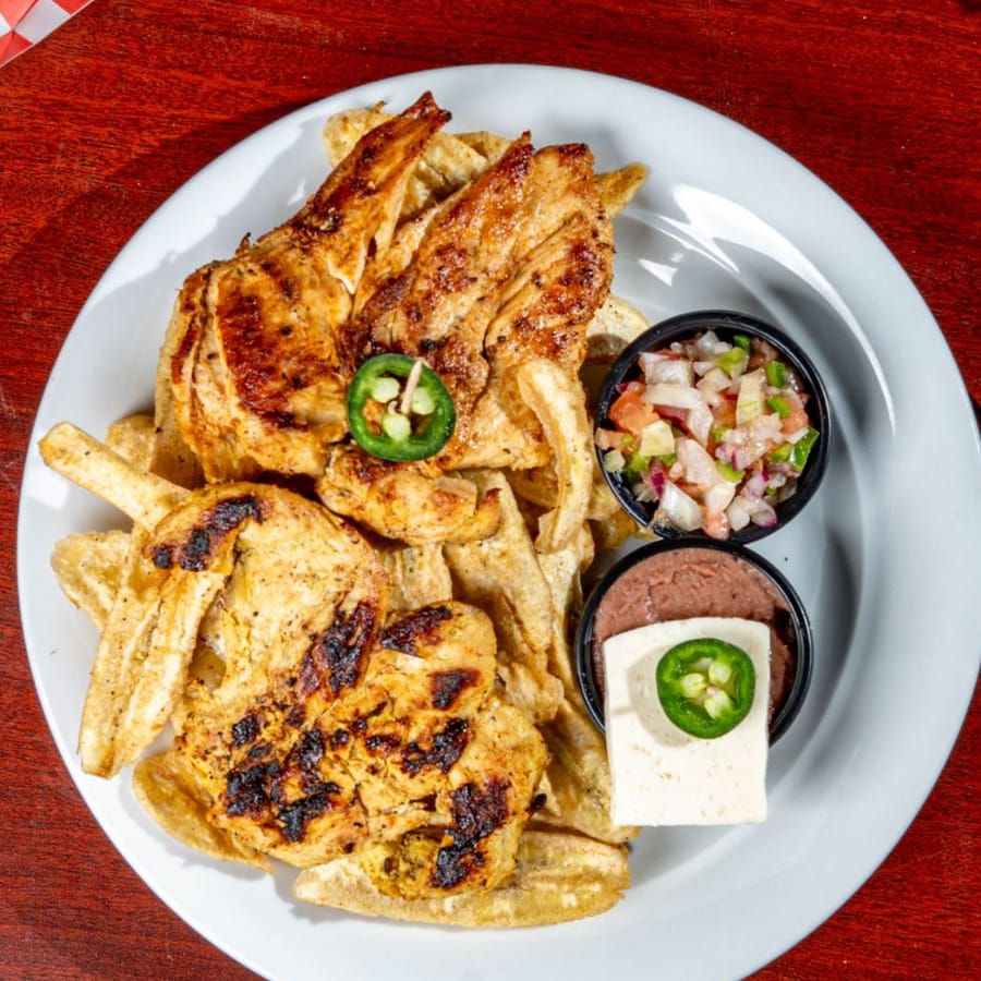 Pollo a la plancha con tajadas de guineo, frijoles, queso y chimol